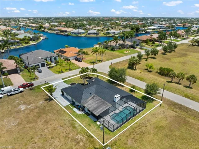 Aerial view of residential area with a nearby body of water and property boundaries highlighted