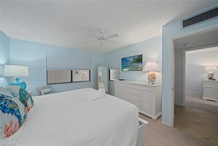 Bedroom with light colored carpet, ceiling fan, a textured ceiling, and light tile patterned floors