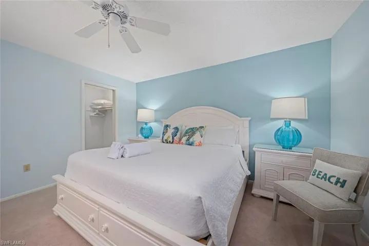 Carpeted bedroom featuring a spacious closet, a textured ceiling, and a ceiling fan