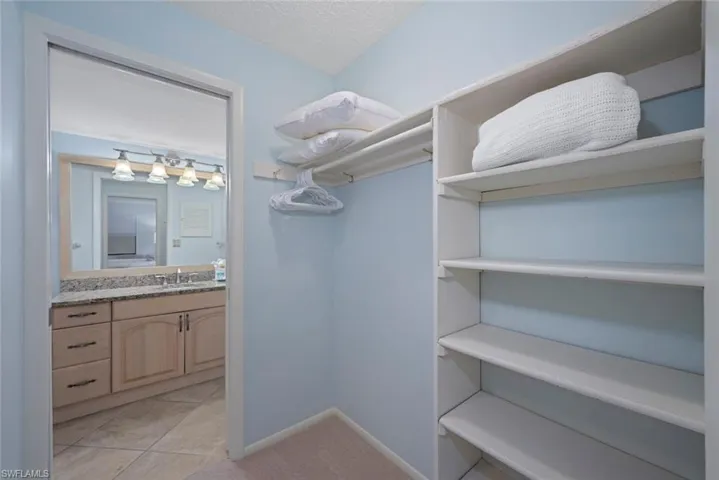 Spacious closet featuring light tile patterned floors and light colored carpet
