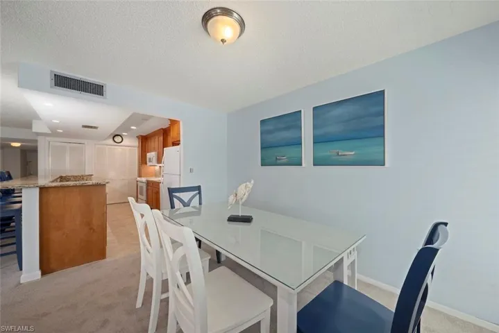 Dining space featuring light colored carpet and a textured ceiling