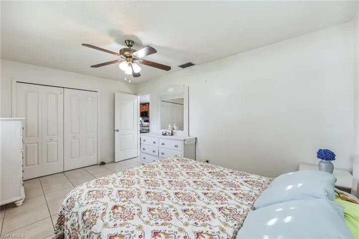 Tiled bedroom featuring ceiling fan and a closet