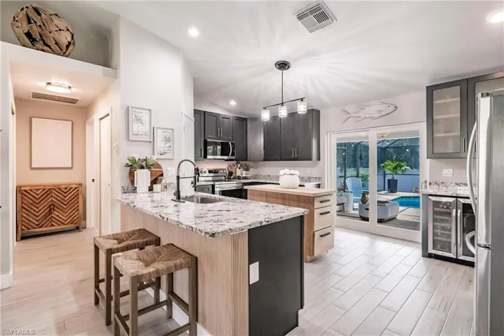 Kitchen with stainless steel appliances, a sink, wine cooler, a peninsula, and a kitchen breakfast bar