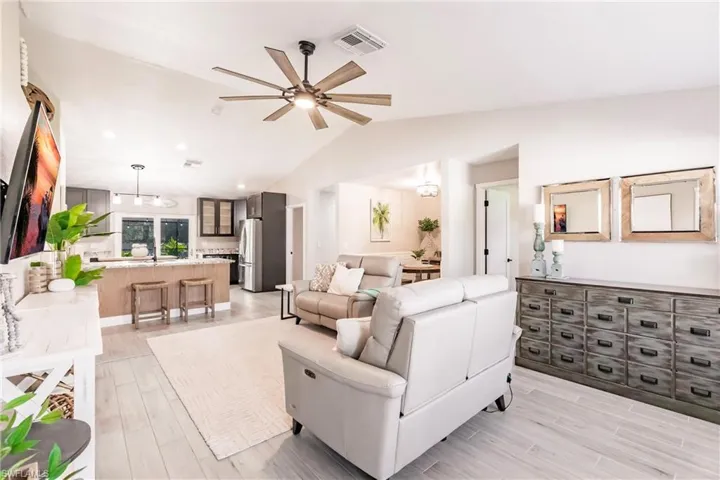 Living room with a ceiling fan, light wood-type flooring, vaulted ceiling, and recessed lighting