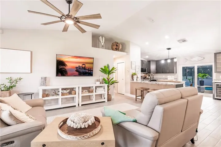 Living room featuring a ceiling fan, vaulted ceiling, recessed lighting, and light wood-style flooring
