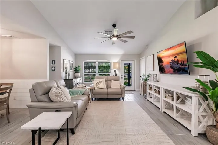 Living room with lofted ceiling, a ceiling fan, and wood finished floors