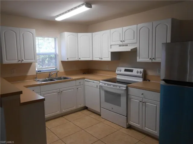 Kitchen with white appliances, white cabinets, and light countertops