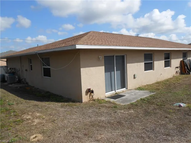 Back of property featuring stucco siding, a shingled roof, and a patio area