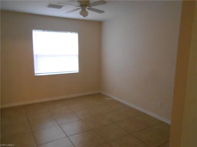 Empty room with light tile patterned floors and ceiling fan
