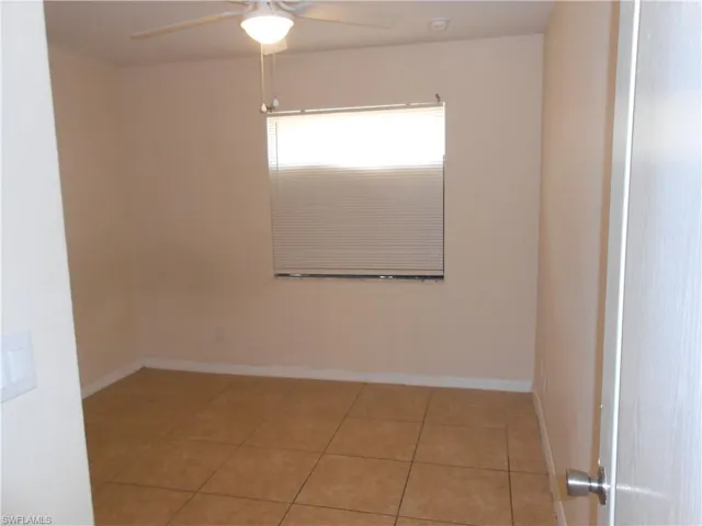 Empty room with light tile patterned flooring and ceiling fan