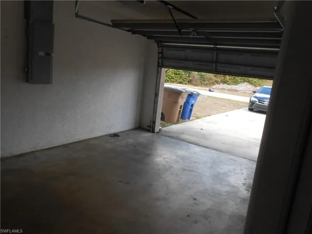 Garage with electric panel and a textured wall