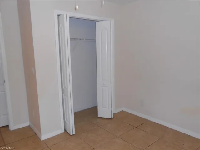 Unfurnished bedroom with a closet and light tile patterned flooring