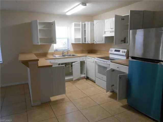 Kitchen featuring white appliances, light countertops, a peninsula, and white cabinets
