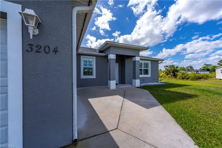 View of exterior entry featuring stucco siding, a yard, and a patio area