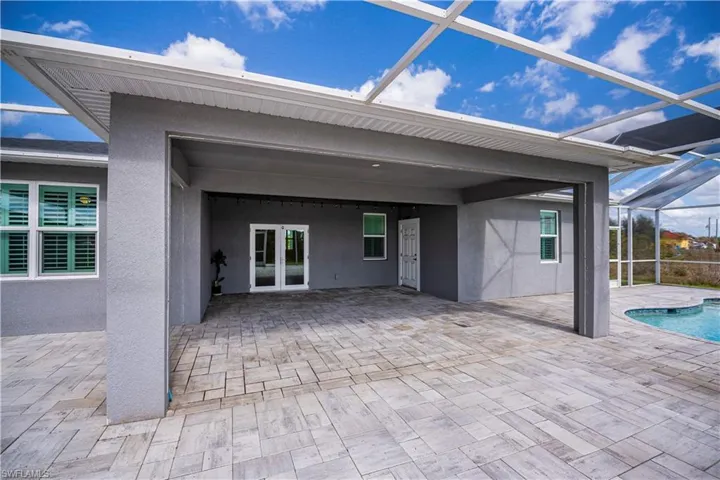 Rear view of property with a patio area, a lanai, stucco siding, an outdoor pool, and french doors