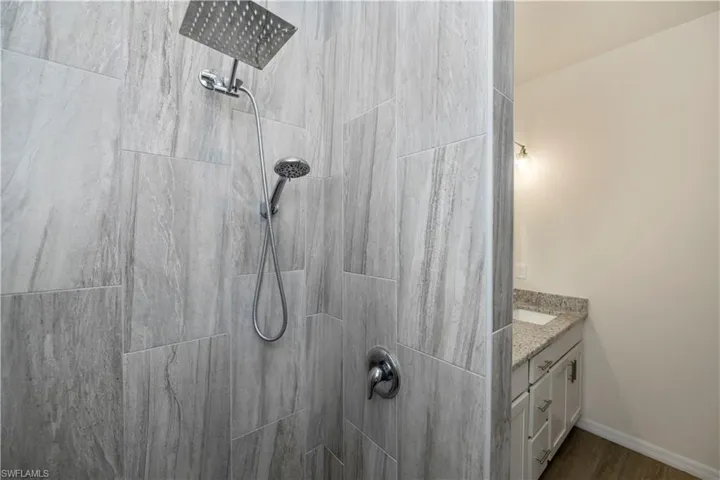 Bathroom with vanity, tiled shower, and wood finished floors