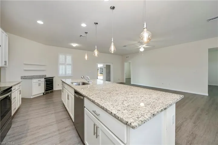 Kitchen with light wood-style flooring, a ceiling fan, white cabinetry, light stone counters, and appliances with stainless steel finishes