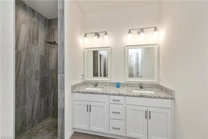 Full bath with double vanity and a tile shower