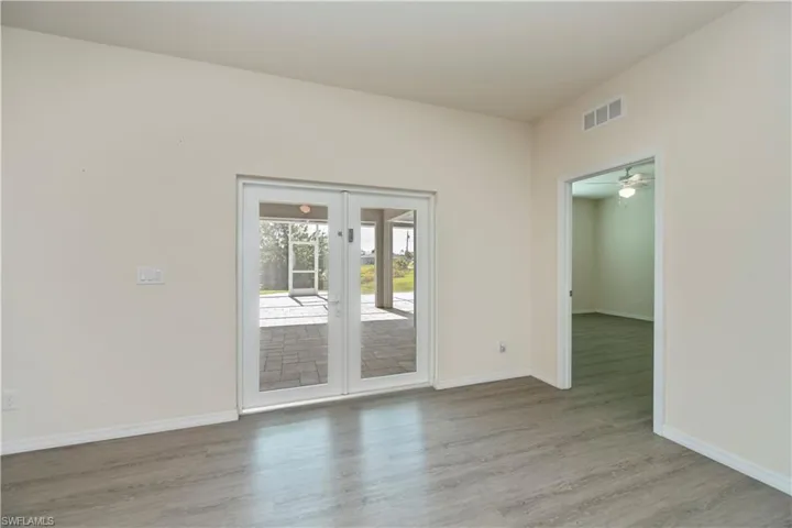 Empty room with wood finished floors, a ceiling fan, and french doors