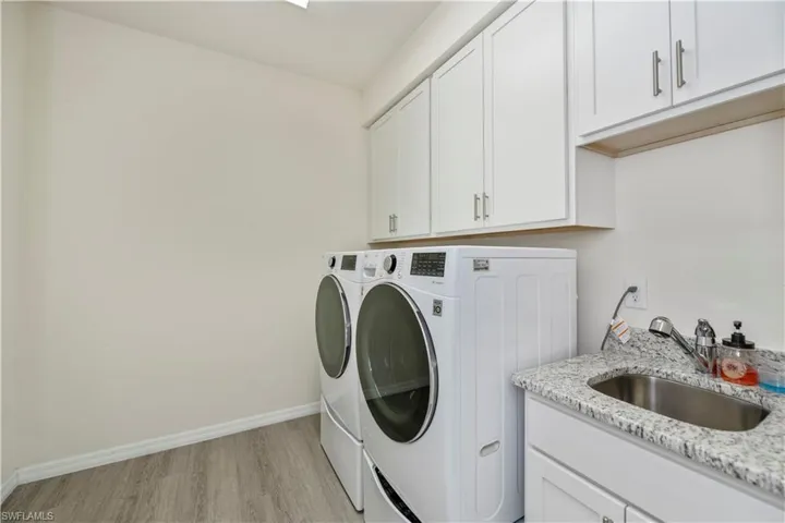 Laundry area with washer and clothes dryer, light wood-type flooring, and cabinet space