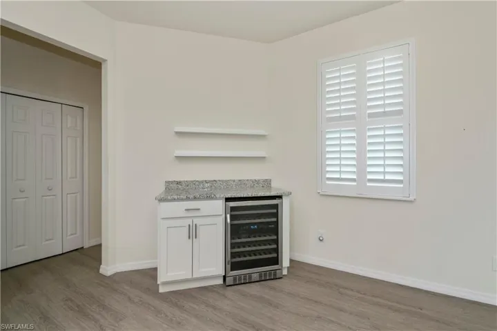 Indoor dry bar featuring beverage cooler and light wood-style flooring