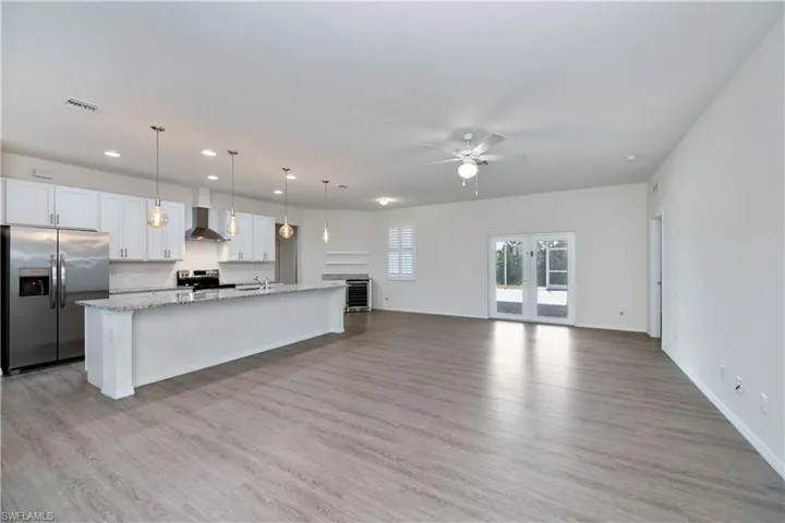 Kitchen with appliances with stainless steel finishes, a ceiling fan, recessed lighting, a center island with sink, and light wood-style flooring