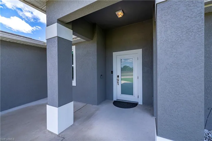 Doorway to property featuring stucco siding and a patio