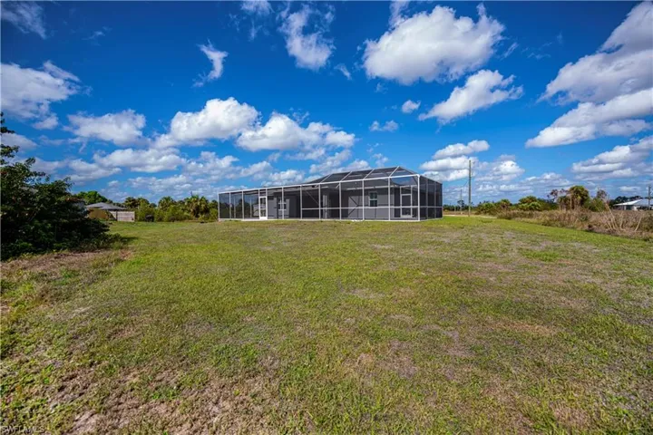 View of grassy yard featuring glass enclosure