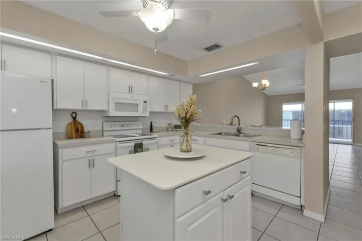 Kitchen featuring light tile patterned flooring, sink, white cabinets, and white appliances