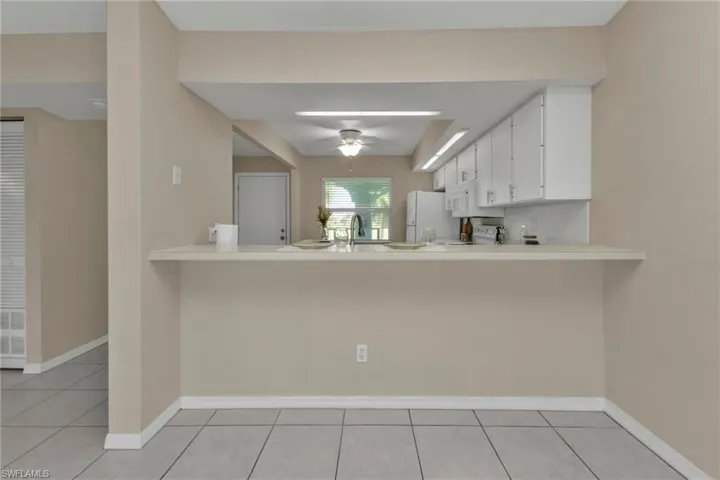 Kitchen featuring white fridge, kitchen peninsula, white cabinets, and ceiling fan