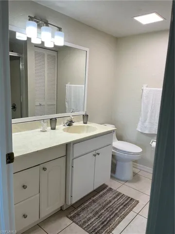 Bathroom with vanity, a shower with shower door, tile patterned floors, and toilet