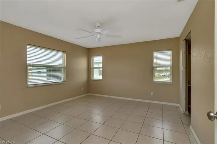 Empty room with ceiling fan and light tile patterned floors