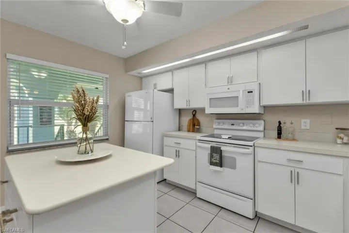 Kitchen featuring white appliances, white cabinetry, backsplash, ceiling fan, and light tile patterned floors