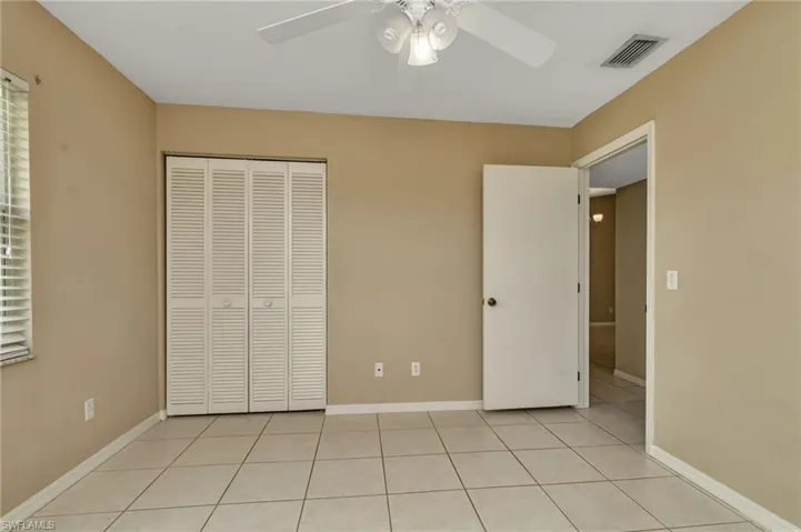 Unfurnished bedroom with ceiling fan, light tile patterned floors, and a closet