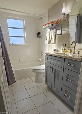 Bathroom featuring vanity, light tile patterned floors, and shower / bathtub combination with curtain