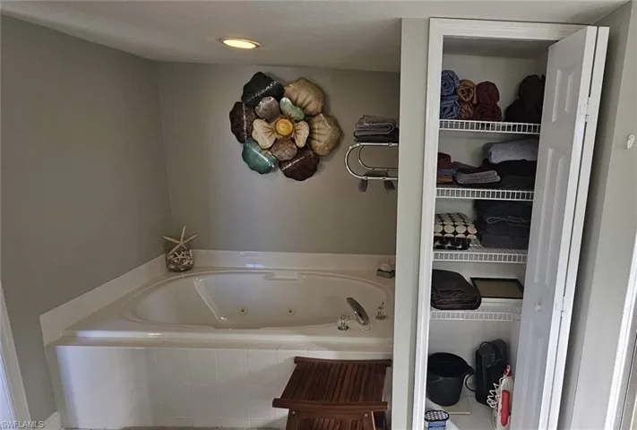 Full bathroom with a whirlpool tub, recessed lighting, and a closet