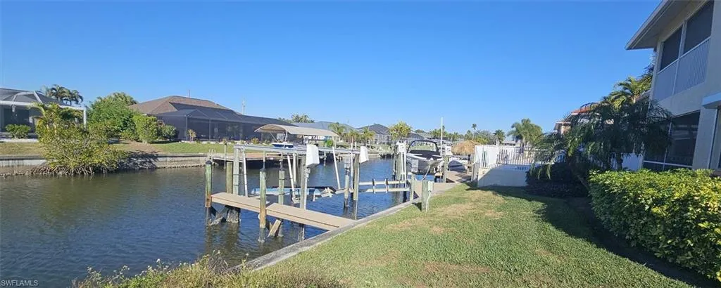 Dock with a water view, boat lift, a lawn, and a residential view