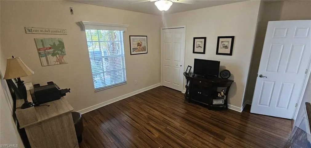 Office with dark wood-style floors and a ceiling fan
