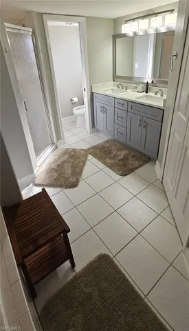 Bathroom featuring double vanity, light tile patterned floors, and a stall shower