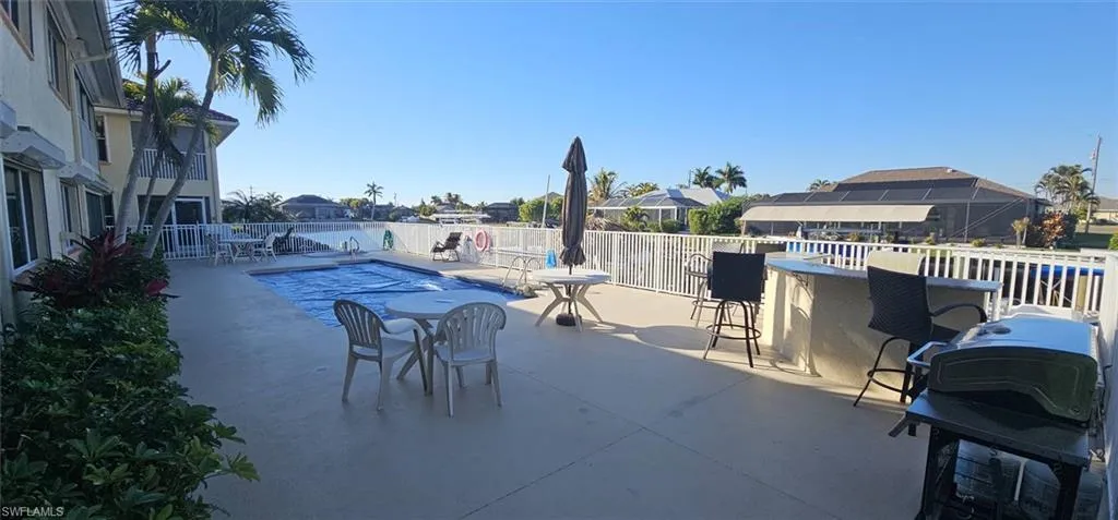 View of patio with a community pool, a residential view, a grill, and exterior bar