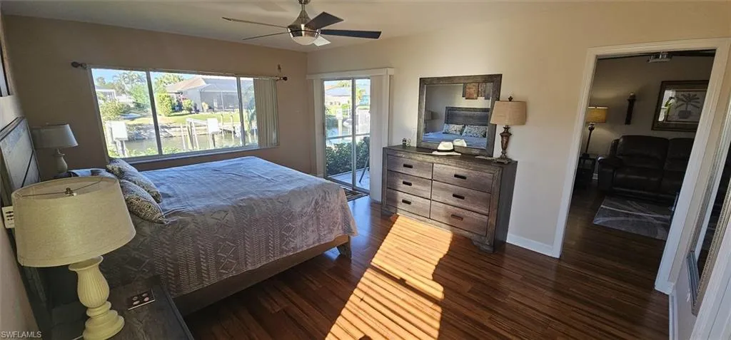 Bedroom with dark wood-style floors, access to outside, and ceiling fan