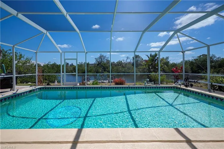Outdoor pool with a sunroom, a lanai, and a water view