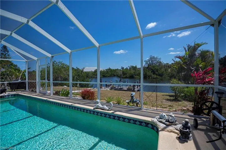 Swimming pool with a sunroom, a water view, and a lanai