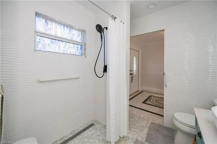 Bathroom with a shower stall, vanity, inlaid floor details, and light tile patterned flooring
