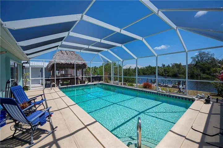 Outdoor pool with a water view, a lanai, a patio area, and a sunroom
