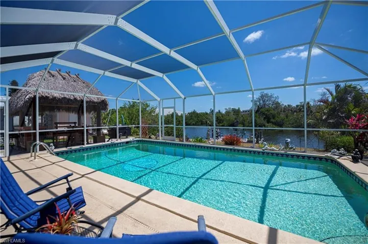 Swimming pool with a water view, a sunroom, and glass enclosure