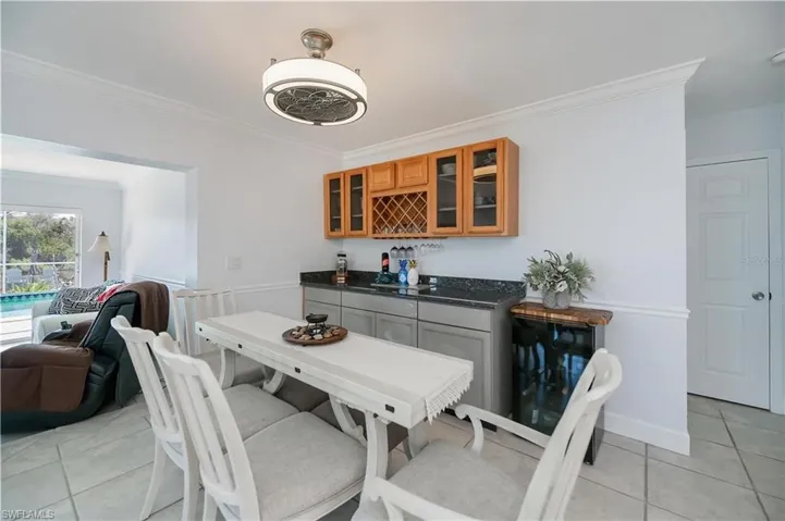 Dining room featuring ornamental molding, light tile patterned flooring, and a dry bar