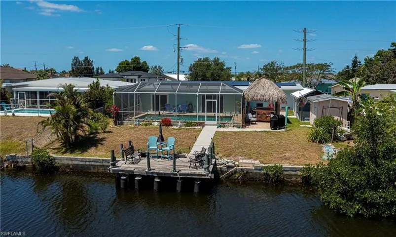 Back of house with a patio area, an outdoor pool, a sunroom, a water view, and a lawn