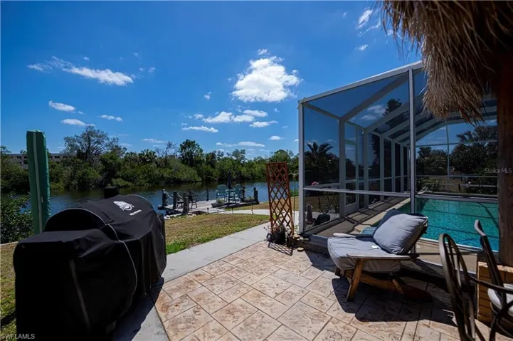 View of patio featuring glass enclosure, a sunroom, a water view, and an outdoor pool
