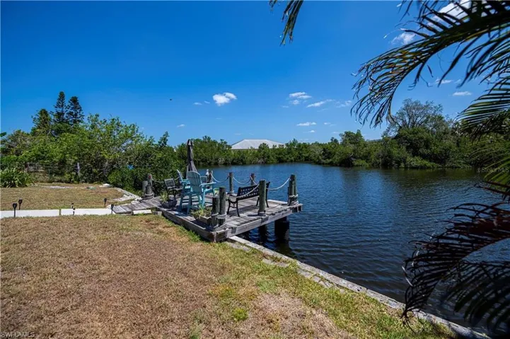 Dock with a yard, a water view, and view of wooded area